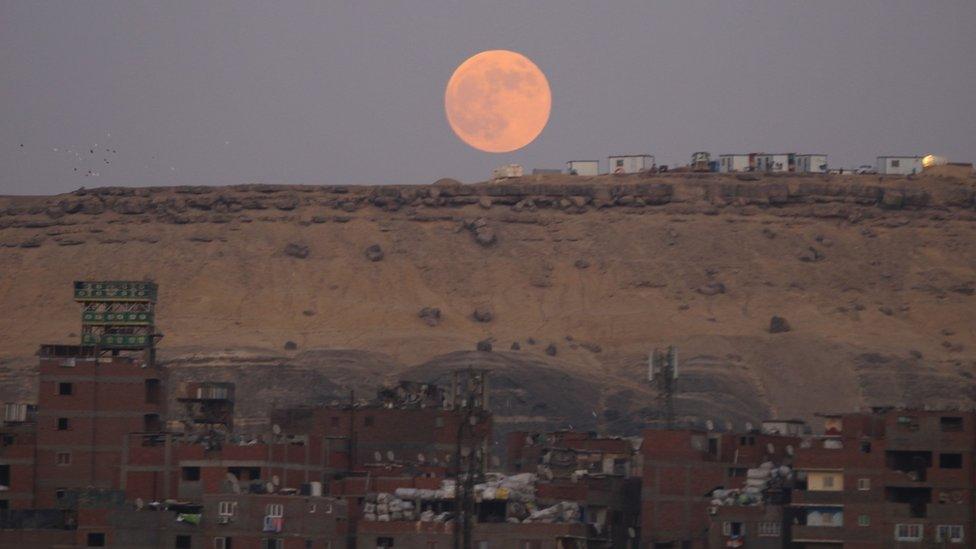 A picture sent by Emad Karim in Cairo, Egypt shows a glowing orange moon above reddish Egyptian sands