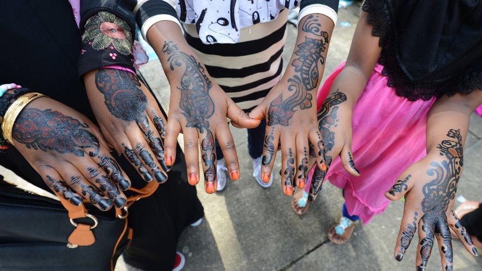 Young Muslim girls show their hands decorated with henna after attending prayers on Eid al-Fitr