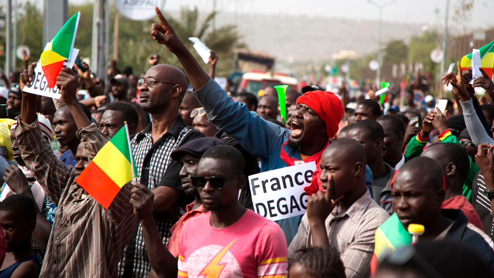 A man in a crowd shouts as he holds a sign that reads, "France get out" during a protest against French and UN forces based in Mali - Bamako, 10 January 2020