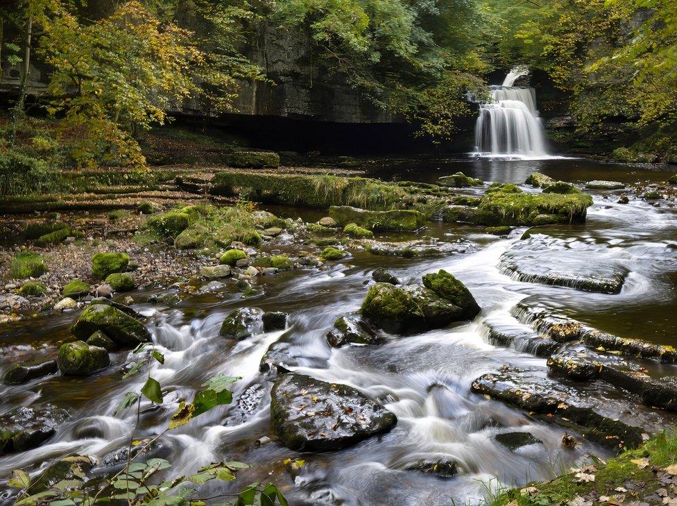 Water runs over a waterfall and between rocks