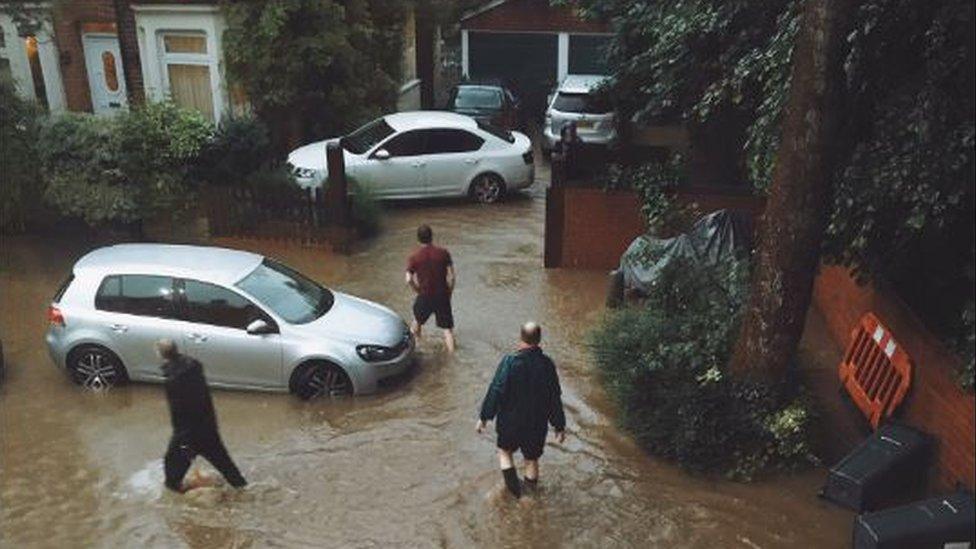 Men wading through water outside their homes