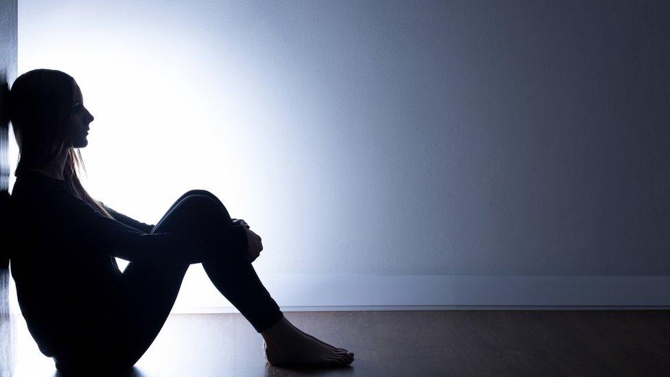 Teenager sitting alone in dark room