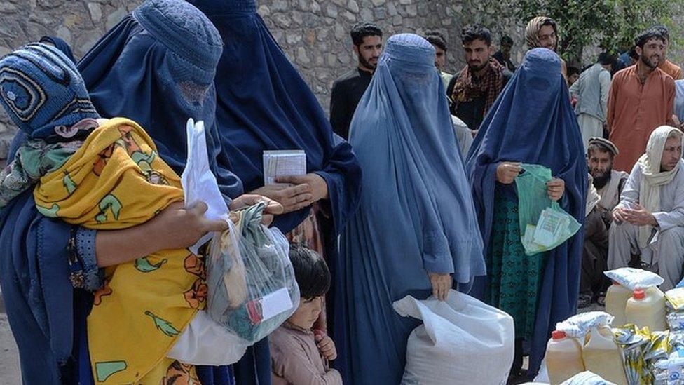 Afghan women receive food donations as part of the World Food Programme (WFP) for displaced people, during the Islamic holy month of Ramadan in Jalalabad on April 20, 2021