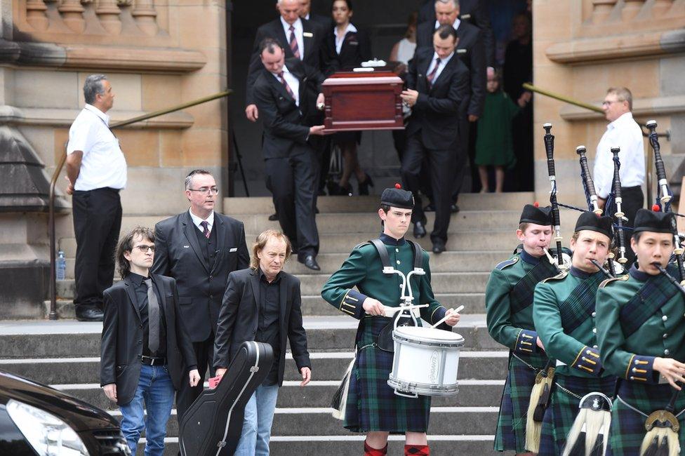 Angus Young, the brother of Malcolm Young, carries a guitar as he leads the casket of his brother Malcolm Young, AC/DC co-founder and guitarist, from St. Mary's Cathedral in Sydney, Tuesday, November, 28, 2017. Malcolm along with his brother Angus Young founded the iconic rock group AC/DC. (AAP Image/Dean Lewins)