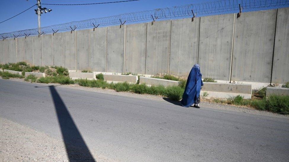 An Afghan clad-burqa woman walks along a road outside a US military base in Bagram on July 1, 2021