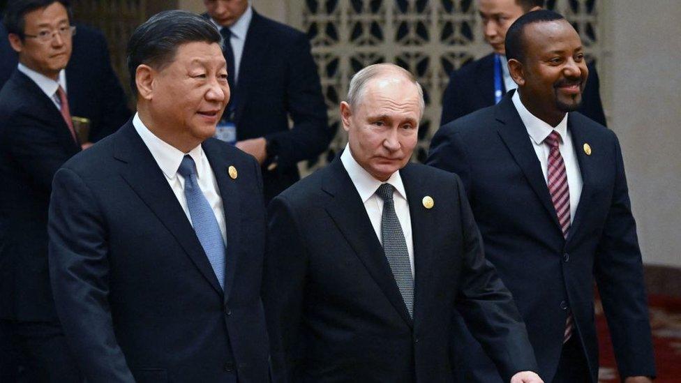 This pool photograph distributed by Russian state owned agency Sputnik shows Russia's President Vladimir Putin and Chinese President Xi Jinping heading to a group photo session during the third Belt and Road Forum for International Cooperation at the Great Hall of the People in Beijing on October 18, 2023.