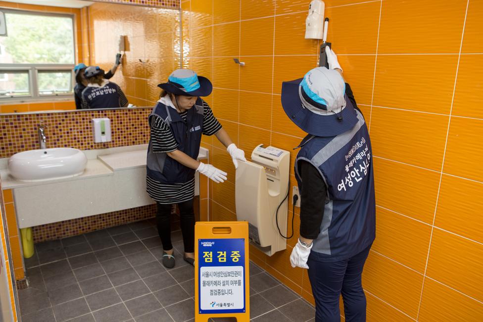 Two women checking toilets in Seoul