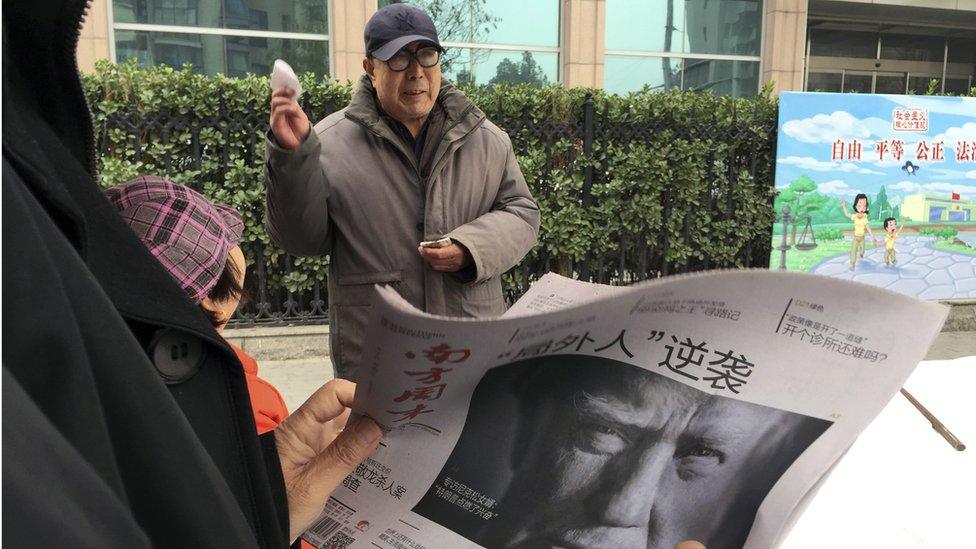 Man in Beijing reads paper featuring picture of Donald Trump