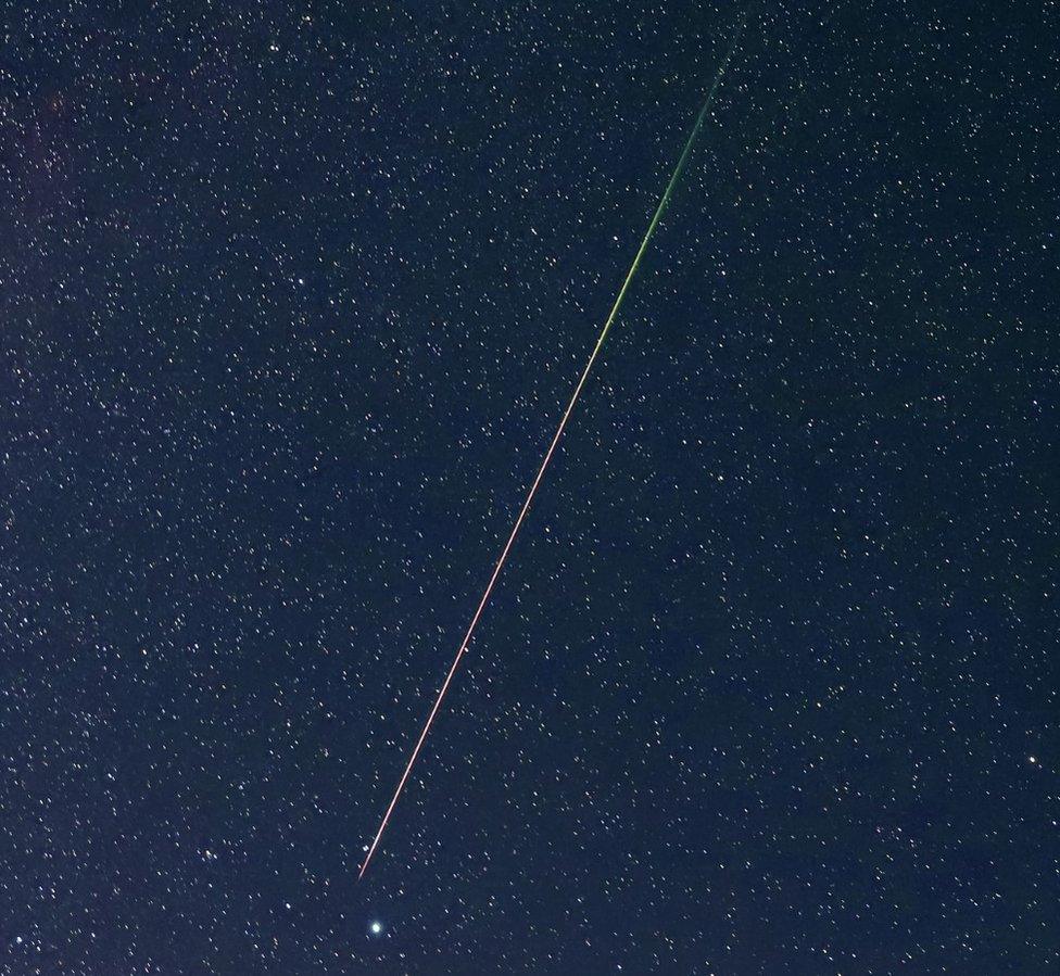 A meteor amid hundreds of stars in the night sky