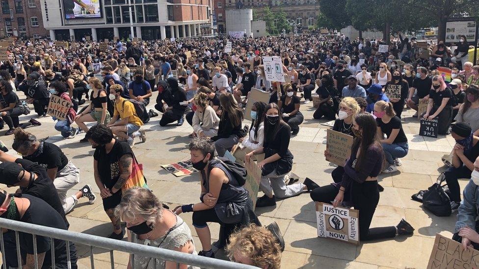 Protesters on the ground bent on one knee