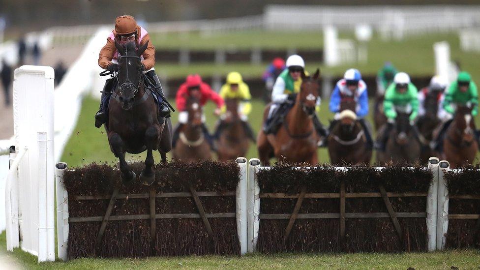 Horses seen approaching and jumping a fence during a race at Wetherby Racecourse, West Yorkshire