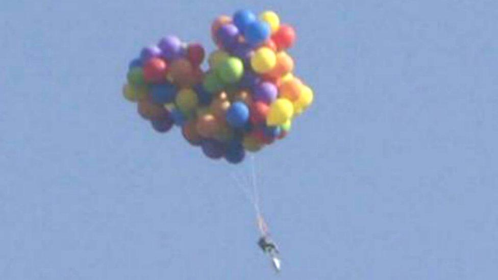 An image of the man flying over Calgary in a chair carried by balloons taken from footage of the incident - 6 July 2015