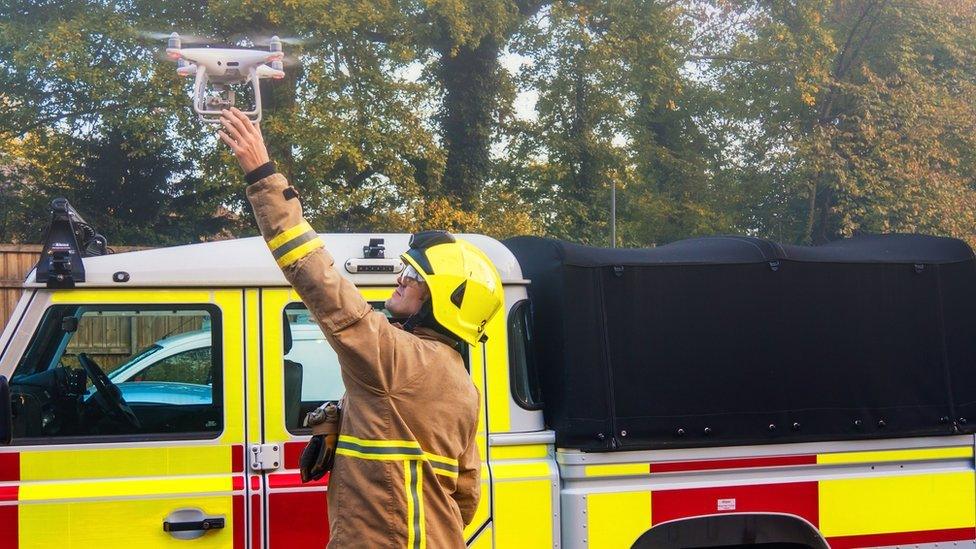 A firefighter flying a drone