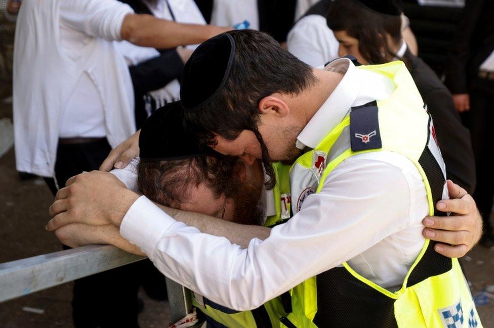 Emergency workers hug as they revisit at the site where dozens were crushed to death in a stampede at a religious festival, pictured on 2 May, 2021