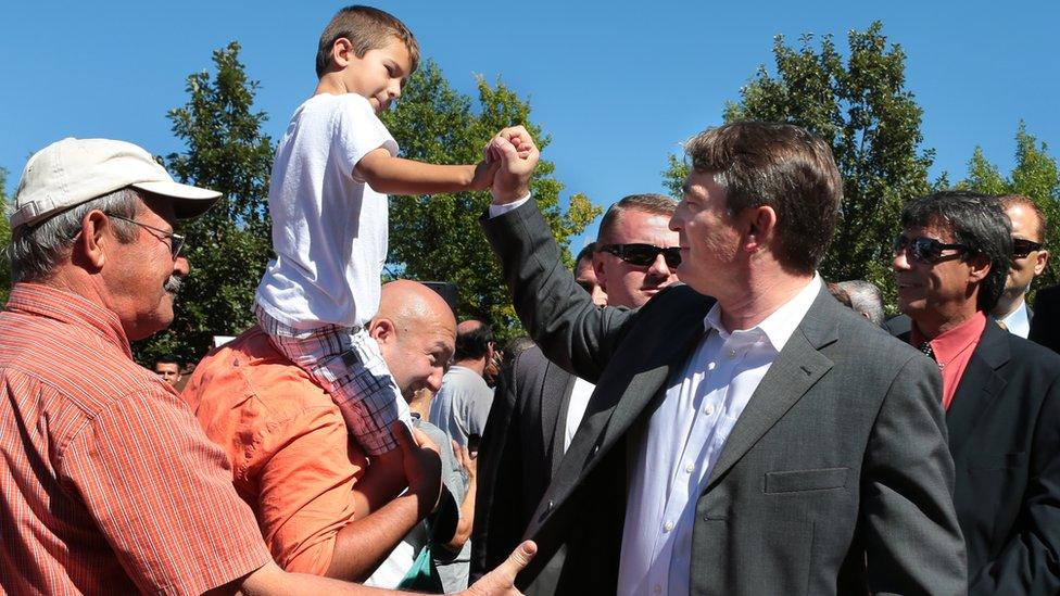 Bosnian President Zeljko Komsic shakes hands with Kenan Jakupovic (riding on the shoulders of his father Sead Jakupovic) following the groundbreaking of a sebilj, a wooden and stone fountain, at the intersection of Morganford and Gravois on Sunday, Sept. 29, 2013