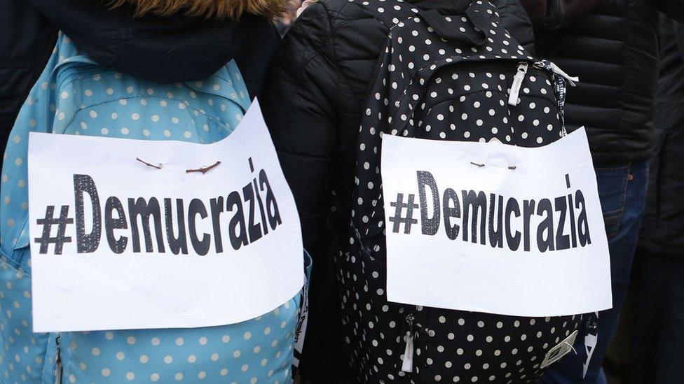 People carry backpacks with signs reading "#democracy" during a demonstration on February 3, 2018 in Ajaccio