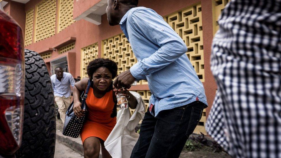 A woman runs for cover in Kinshasa