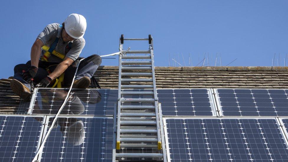 Man installing a solar panel on a roof