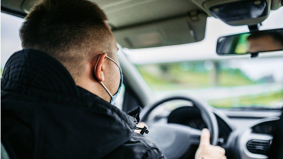 A taxi driver wearing a face covering