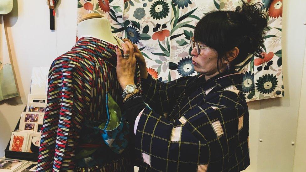 Image of Yumiko Jones dressing a mannequin in a Kimono