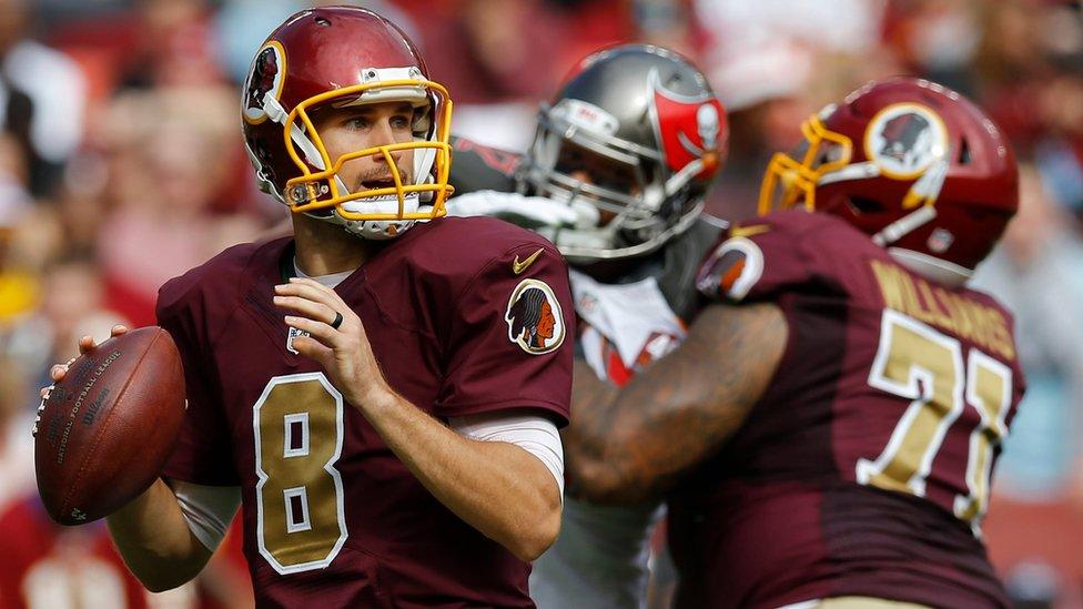 A player dressed in the Washington Redskins uniform prepares to throw an American football