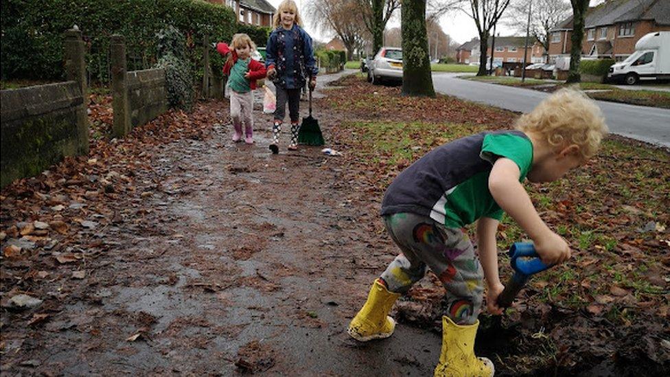 child sweeping leaves