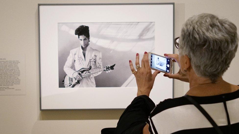 Visitors look at a 1993 photograph of musician Prince by Lynn Goldsmith at the Smithsonians National Portrait Gallery on April 22, 2016 in Washington, DC