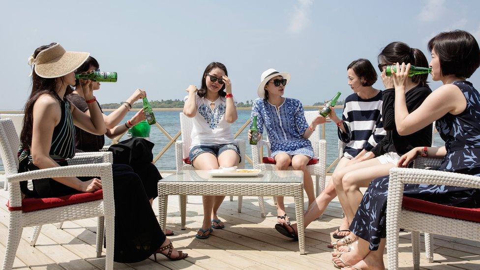 A group of Chinese female tourists gather at a jetty bar in Maldives