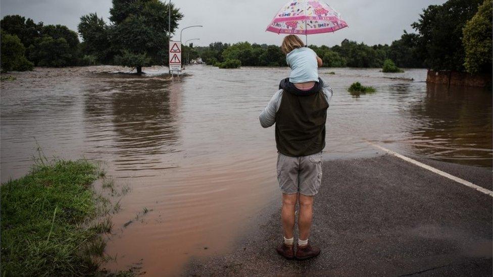 A man with his daughter look out over a flooded area in Centurion, Pretoria, South Africa, 09 December 2019