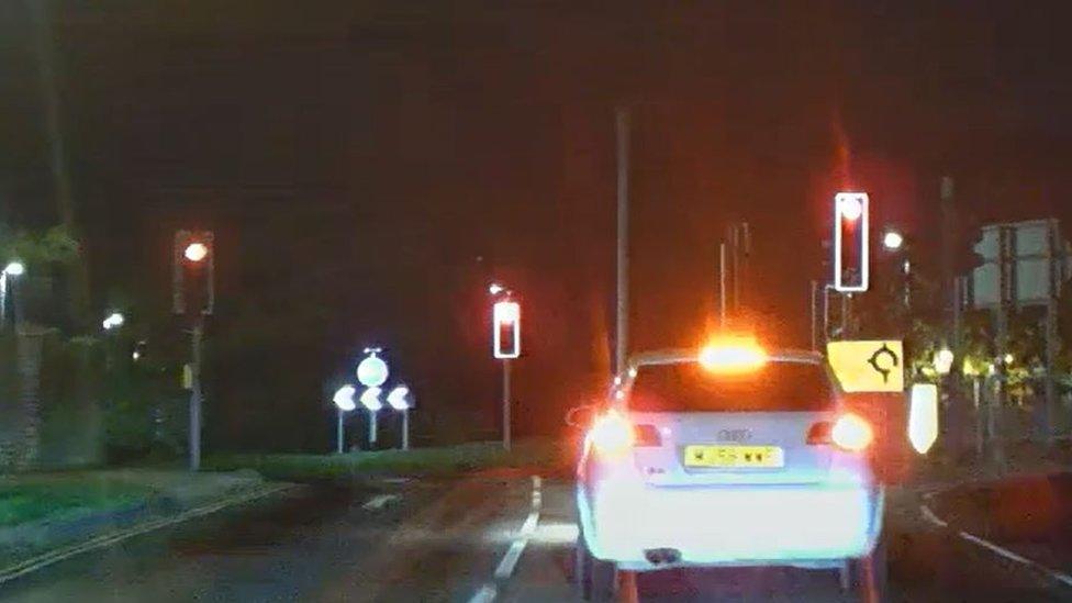 The back of a white Audi car approaching traffic lights on red