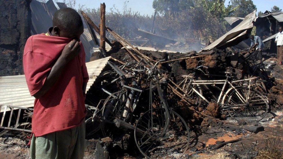 A man wipes his face in front of a church where some 30 people were burned alive in Eldoret, Kenya (1 January 2008)