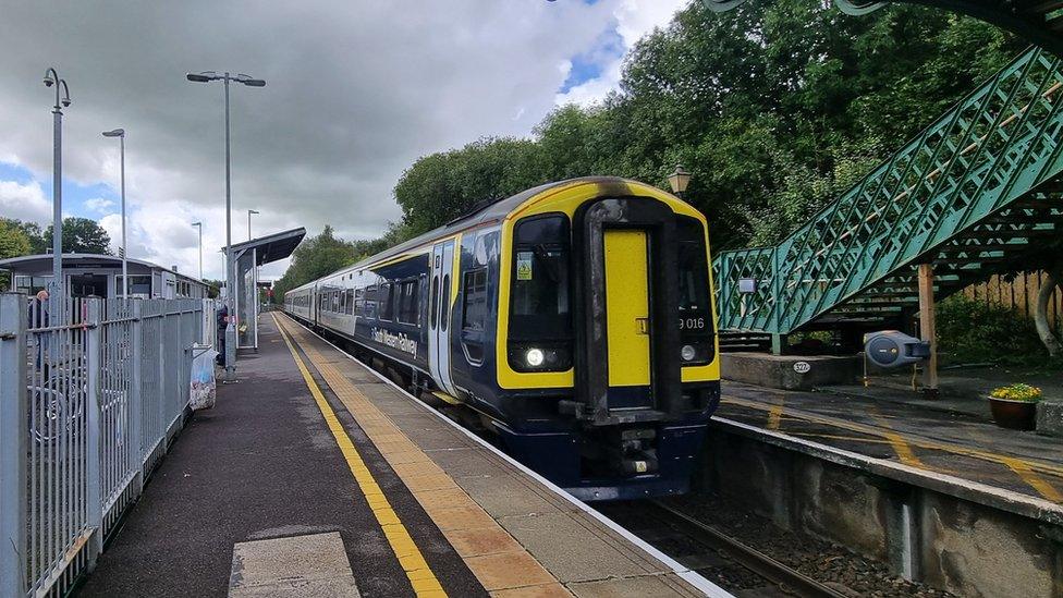 a black, navy and yellow South Western Railway train at the platform at Templecombe Station