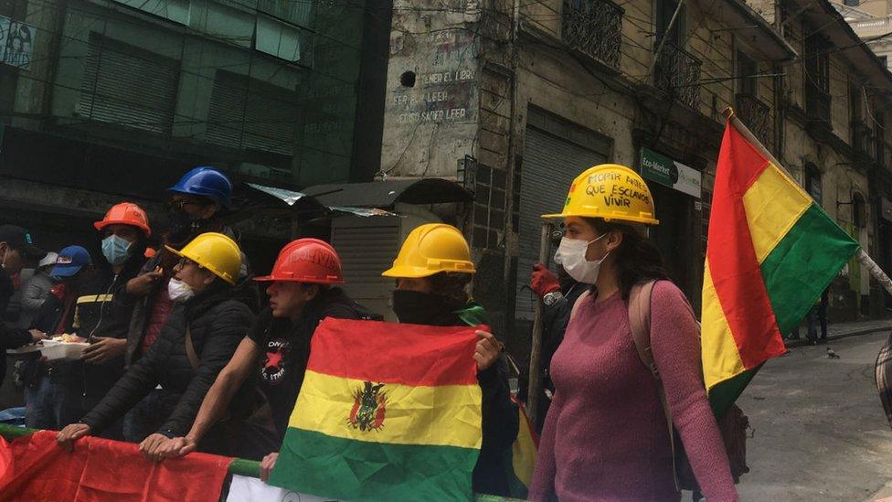 A group of protesters wearing hard hats man a barricade near Mr Morales' home and office