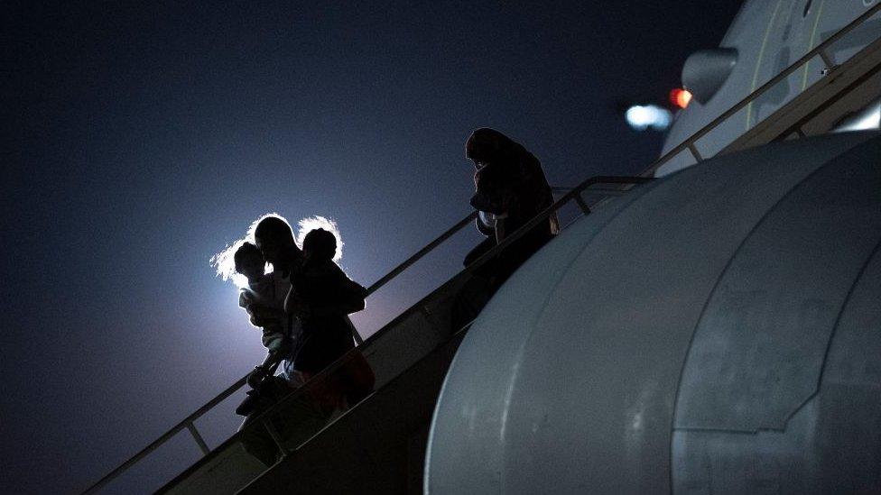 Passengers evacuated from Afghanistan leave a plane that has brought them to the UK.