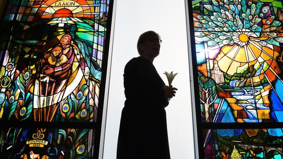 The stained glass memorial window the a woman standing holding a lily