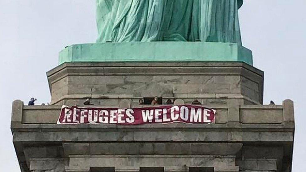 A giant banner saying "Refugees Welcome" hangs on the pedestal of the Statue of Liberty, New York, 21 February 2017