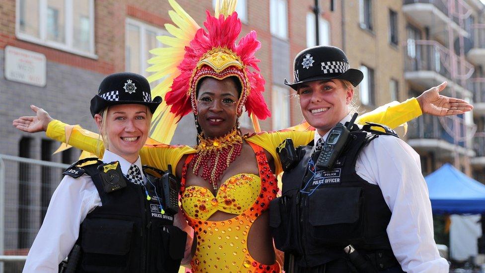 Police officers stand with a carnival performer