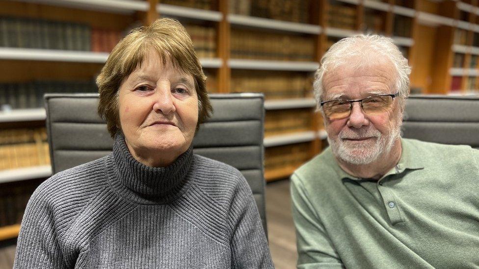 Roger & Pauline look at the camera, Roger in a green t-shirt and Pauline a grey jumper