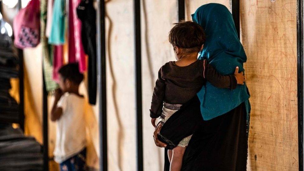 Sara al-Abdullah carries an orphan at a camp in the northern Syrian village of Ain Issa, on 26 September 2019.