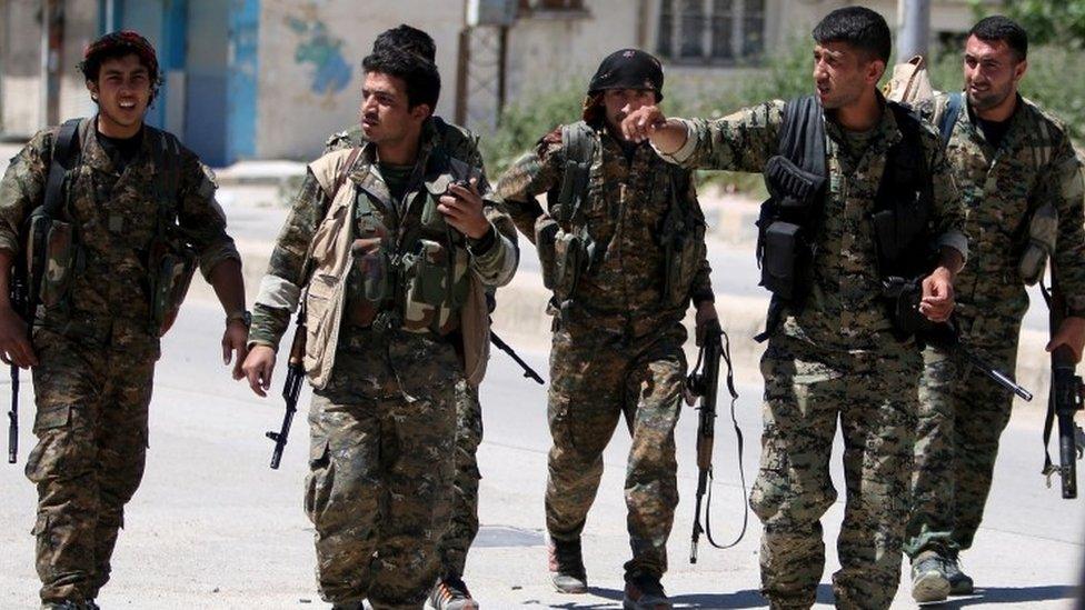 Kurdish fighters from the People's Protection Units (YPG) walk along a street in the southeast of Qamishli city, Syria (22 April 2016)