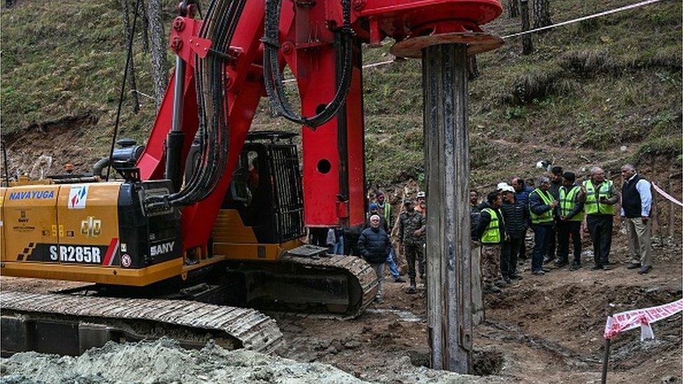 India's Minister of State of Road Transport and Highways VK Singh (R) inspects earth boring machine deployed to drill a vertical hole into the collapsed tunnel to rescue the 41 men trapped in the Silkyara, days after it collapsed in the Uttarkashi district of India's Uttarakhand state on November 26, 2023.