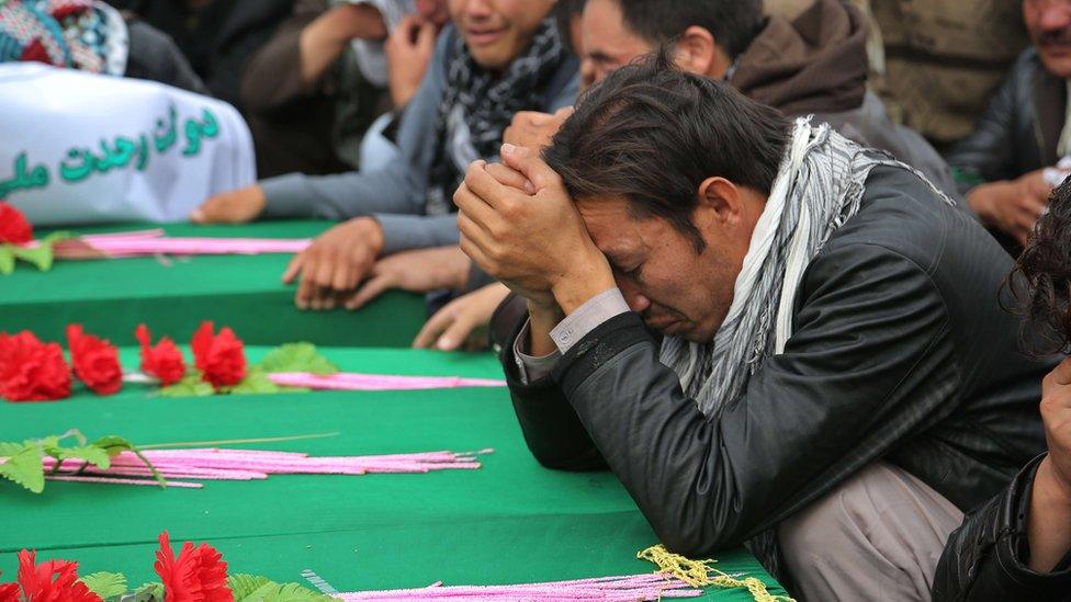 Afghan men mourn the seven victims whose throats were cut by unidentified militants over the weekend