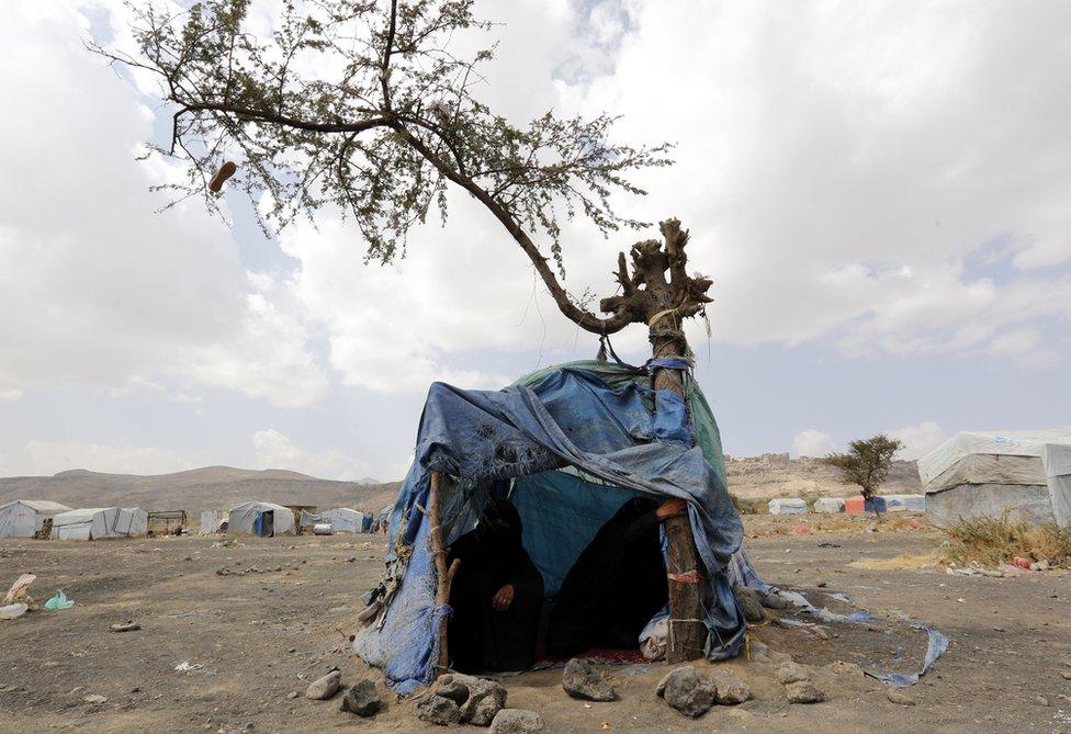 Two women sit by a makeshift bed