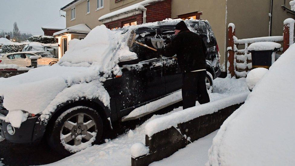 A motorist clears the snow from a 4x4 vehicle in Bristol