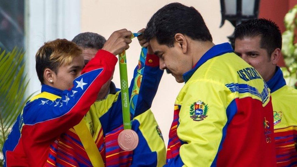 Venezuelan boxer Yoel Finol, who won bronze in the Men's fly 52kg event at the Rio 2016 Olympic Games, places the medal around the neck of Venezuelan President Nicolas Maduro (right) during a welcome ceremony in Caracas