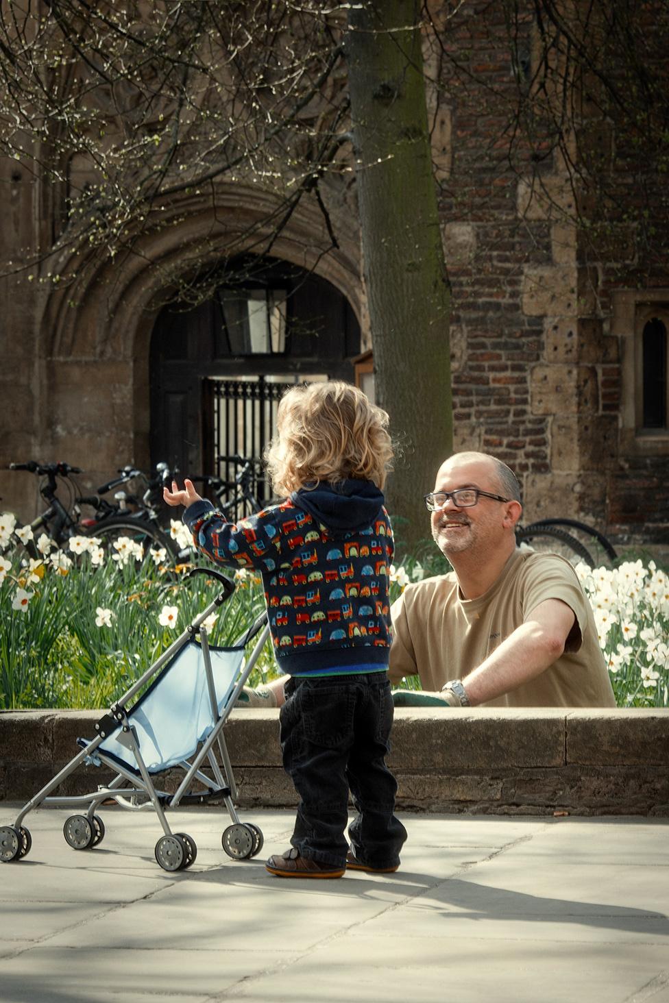 Child with a buggy talking to a gardener