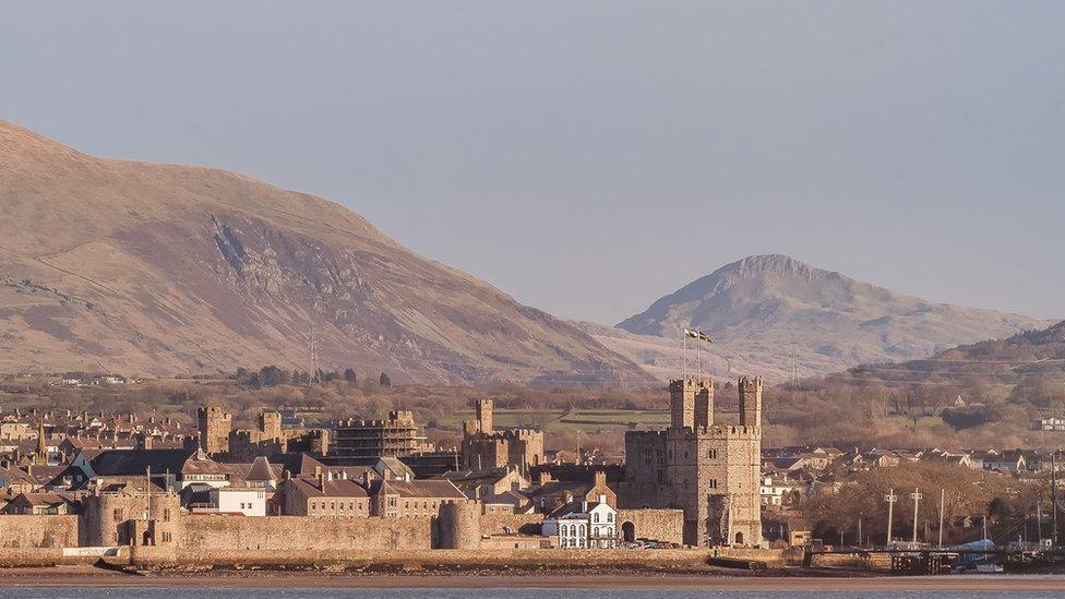 Castell Caernarfon yn yr haul o dan awyr las