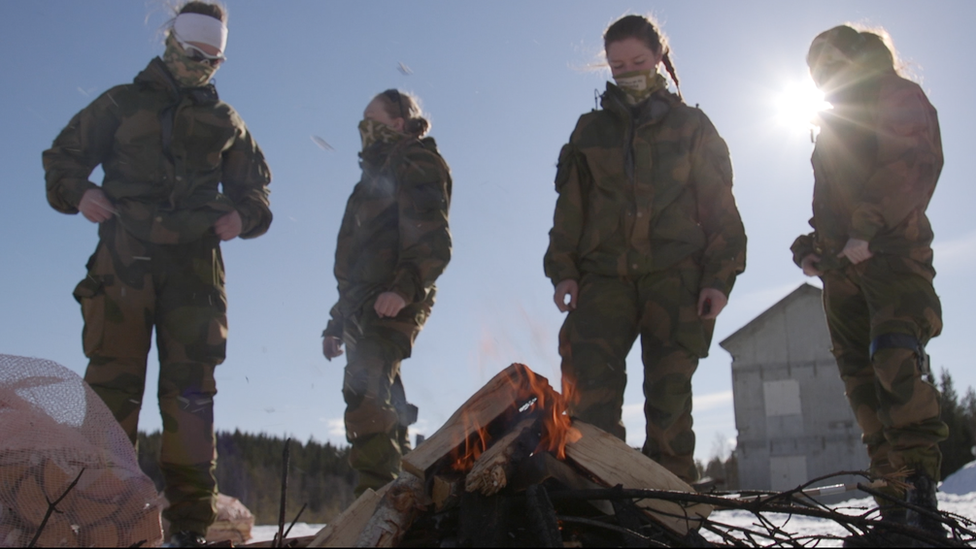 Soldiers stand around a fire