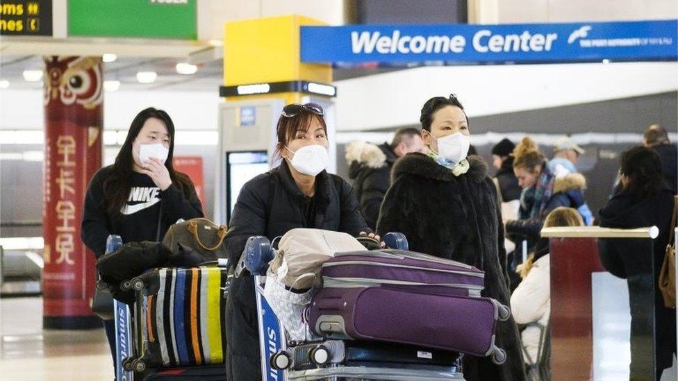 Visitors wearing medical masks arrive at New York's JFK airport