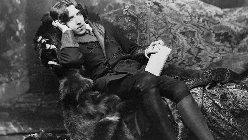 Oscar Wilde on a couch in thought.